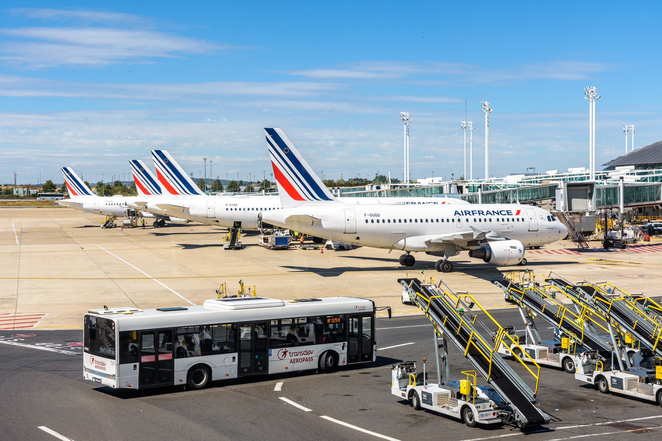Eine Reihe von Air France Flugzeugen steht in Parkposition nebeneinander, im Vordergrund bringt ein Bus Passagiere zu den Maschinen.