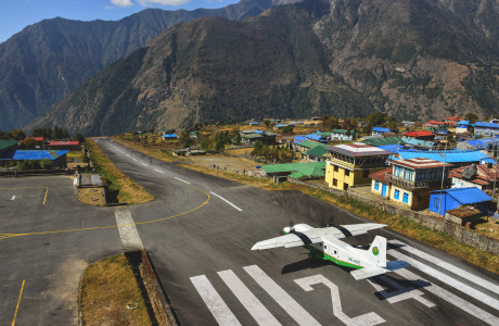 Die Startbahn in Lukla bei gutem Wetter, eine Propellermaschine beginnt gerade den Start.