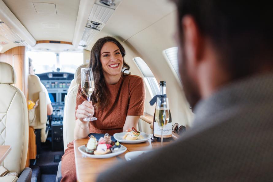 Eine Frau in einem Privatjet trinkt Champagner.